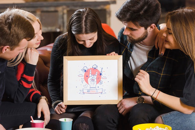 Free Friends Looking At A Frame Mock-Up While Holding It Psd