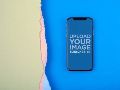 iPhone X Mockup Lying on a Blue Surface Near Broken Paper
