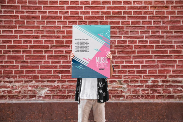 Free Man Presenting Poster Mockup In Front Of Brick Wall Psd