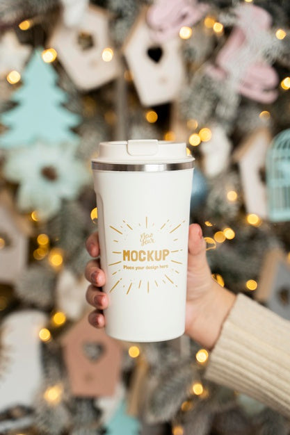 Free Person Holding Mug Next To Christmas Decorations Psd
