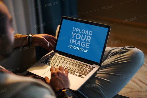Free Mockup of a Man Using a MacBook in a Cozy Living Room