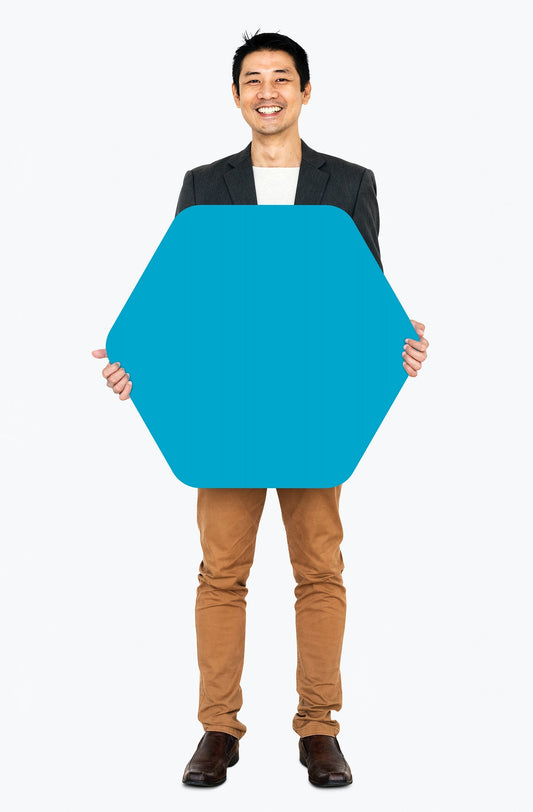 Free Cheerful Man Showing A Blank Blue Hexagon Shaped Board