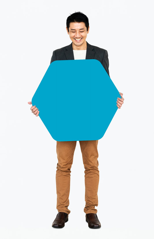 Free Cheerful Man Showing A Blank Blue Hexagon Shaped Board