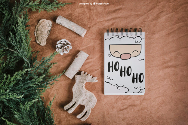 Free Christmas Mockup With Notepad Next To Fir Psd