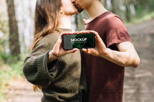 Free Cute Couple In Nature With Smartphone Mock-Up Psd