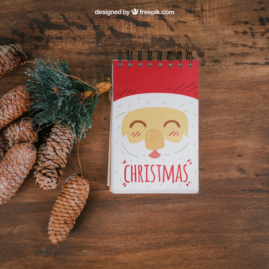 Free Decorative Christmas Mockup With Notepad And Pine Cones Psd
