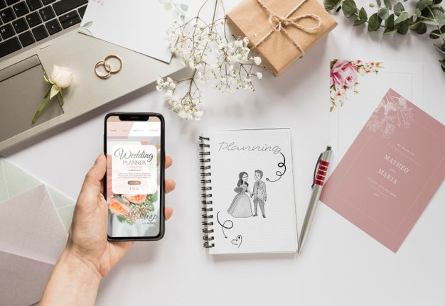 Free Fat Lay Of Hand Holding Smartphone And Wedding Essentials Psd