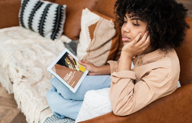 Free Female Sitting On Couch With Tablet In Her Hand And Looking Away Psd