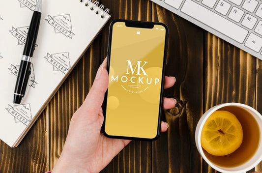 Free Flat Lay Hand Holding Smartphone Mock-Up With Tea On Desk Psd