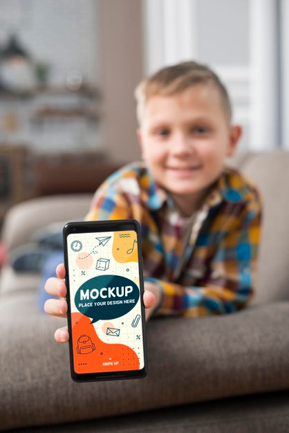 Free Front View Of Defocused Kid On Couch Holding Smartphone Psd
