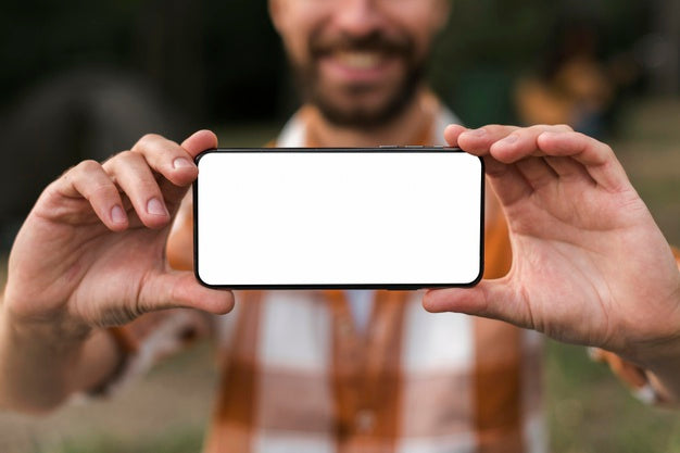 Free Front View Of Defocused Smiley Man Holding Smartphone While Camping Psd