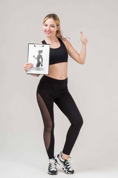 Free Front View Of Smiley Fitness Woman Holding Notepad And Giving Thumbs Up Psd