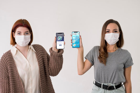 Free Front View Of Women With Masks Holding Smartphones Psd