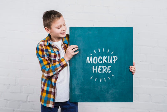 Free Front View Young Kid Holding Mock-Up Sign Psd