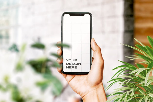 Free Hand Holding New Smartphone Mockup Surrounded By Leaves Psd