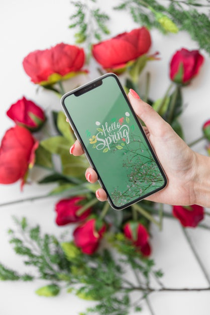 Free Hand Holding Smartphone Mockup Above Flowers Psd