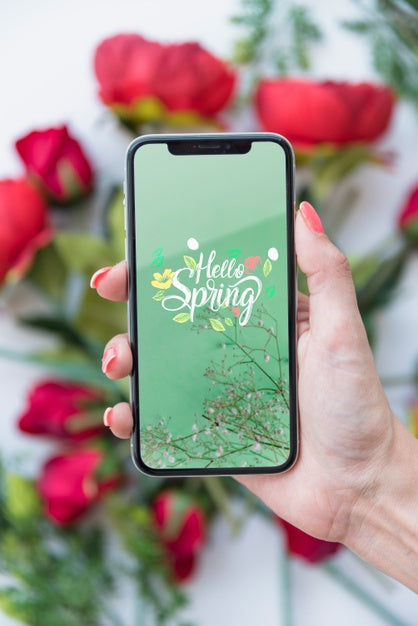 Free Hand Holding Smartphone Mockup Above Flowers Psd