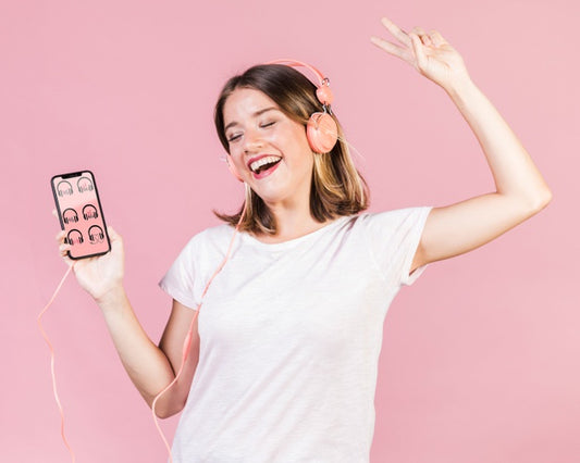 Free Happy Young Woman With Headphones Holding A Cellphone Mock-Up Psd