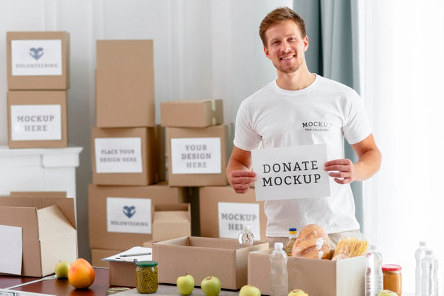 Free Male Volunteer Holding Blank Paper With Food Boxes For Donation Psd