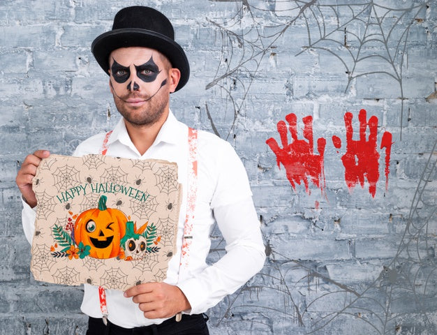 Free Male With Make-Up Holding A Card With Pumpkin For Halloween Psd