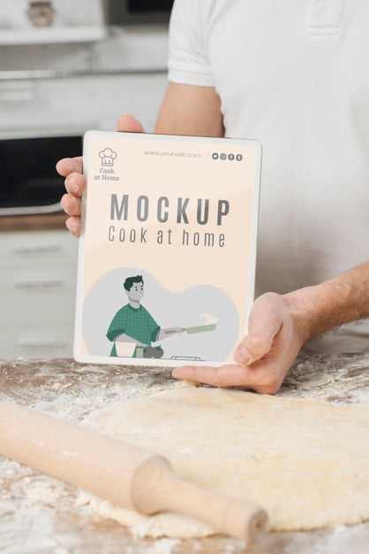 Free Man Holding Book While Rolling Dough In The Kitchen Psd