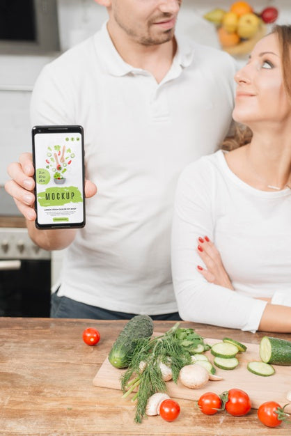 Free Man Holding Smartphone In The Kitchen While Cooking With Woman Psd