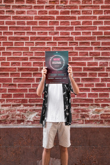 Free Man Presenting Poster Mockup In Front Of Brick Wall Psd