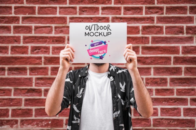 Free Man Presenting Poster Mockup In Front Of Brick Wall Psd