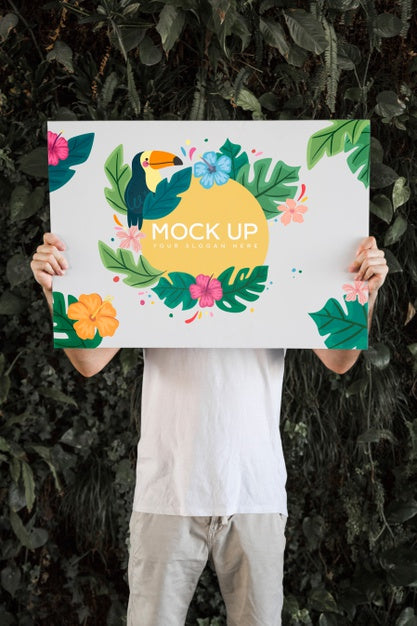 Free Man Presenting Poster Mockup In Front Of Leaves Psd