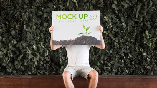 Free Man Presenting Poster Mockup In Front Of Leaves Psd