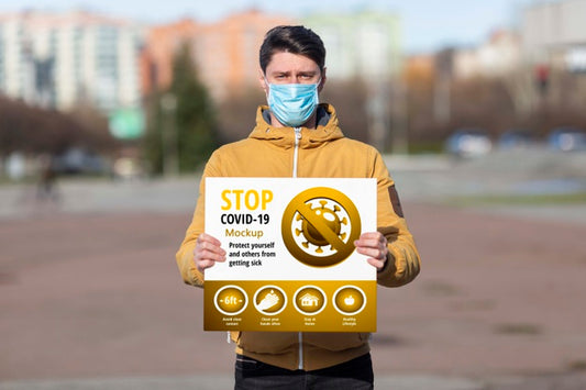 Free Man Wearing A Mask Holding A Coronavirus Stop Mock-Up Psd
