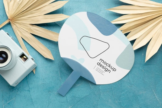 Free Paper Mock-Up Hand Fan With Dry Leaves And Camera Psd