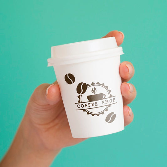 Free Person Holding Up A Coffee Paper Cup On Blue Background Psd