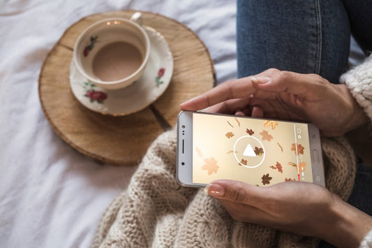 Free Person On Bed Looking At Smartphone With Autumn Concept Psd