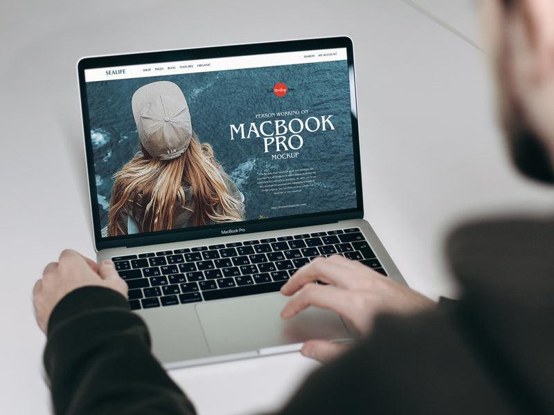 Free Person Working On Macbook Pro Mockup – CreativeBooster