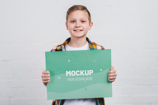 Free Portrait Of Smiley Kid Holding Mock-Up Sign Psd