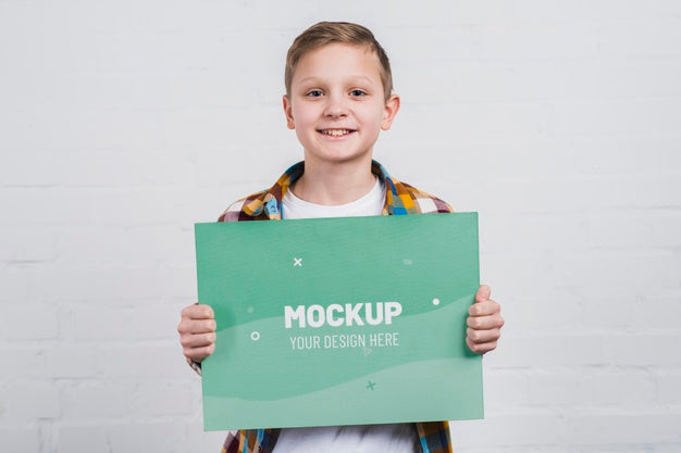 Free Portrait Of Smiley Kid Holding Mock-Up Sign Psd