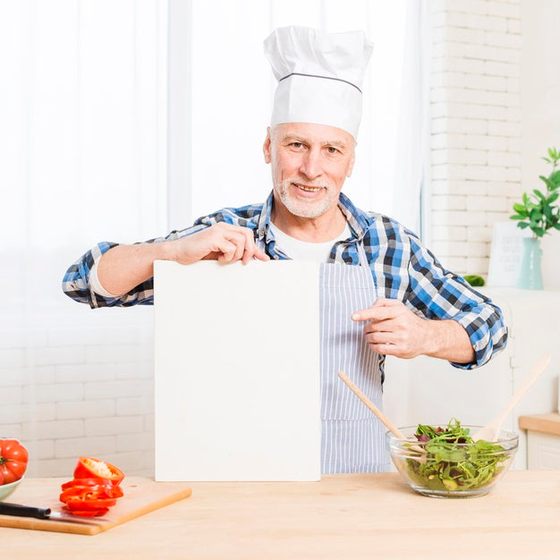Free Senior Male In Kitchen Holding Paper Mock-Up Psd