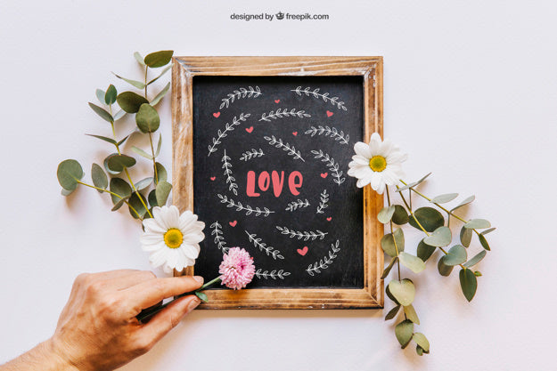 Free Slate Mockup With Hand Placing Flowers Psd