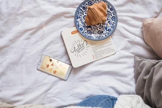 Free Smartphone On Bed With Diary And Croissant Psd