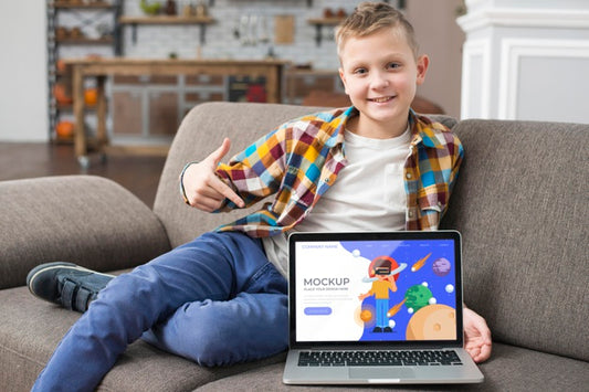Free Smiley Kid On Couch Pointing At Laptop Psd