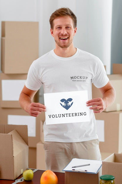 Free Smiley Male Volunteer Holding Blank Paper With Food Boxes For Donation Psd