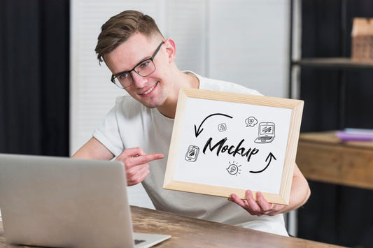 Free Smiley Man Holding Mock-Up Frame With Open Laptop Psd