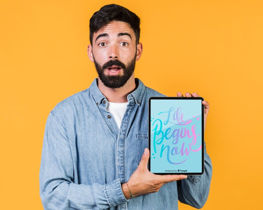 Free Surprised Young Man Holding A Tablet Mock Up Psd