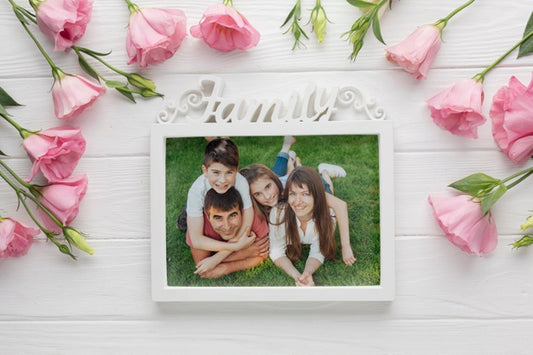 Free Top View Of Family Frame And Flowers On Wooden Background Psd