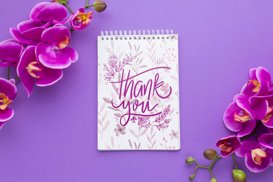 Free Top View Of Notebook And Flowers On Purple Background Psd