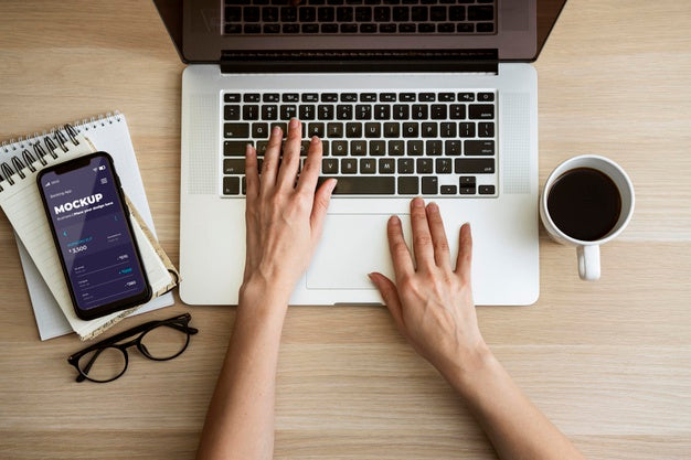 Free Top View Person Using Laptop Near Phone Mock-Up Psd