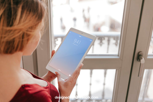 Free Woman Using Tablet In Front Of Window Psd