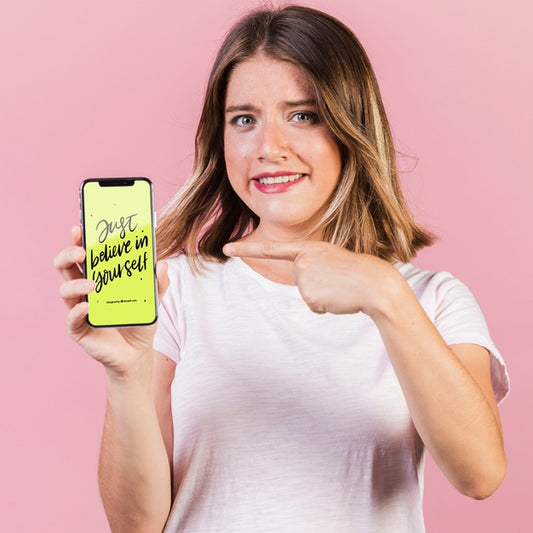 Free Young Woman Pointing Finger At A Cellphone Mock-Up Psd